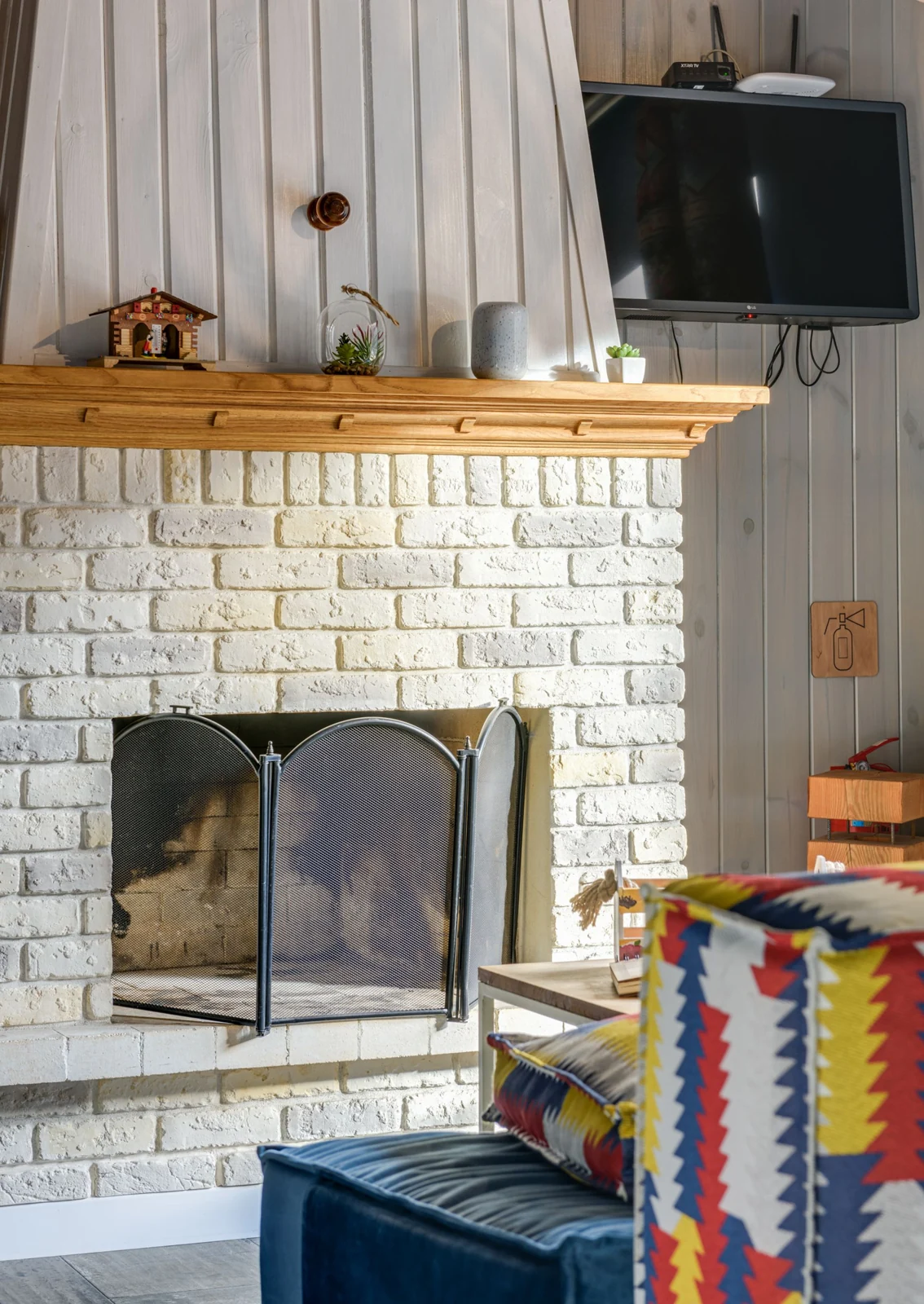 White brick fireplace with a wood mantel and mesh screen